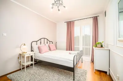 a bedroom with a bed with pink pillows and a window at Apartament Clover by Meadow Stay Apartments in Kraków