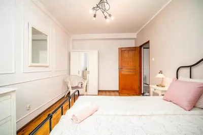a white bedroom with a bed and a chair at Apartament Clover by Meadow Stay Apartments in Kraków