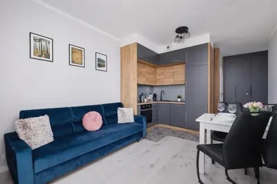 a living room with a blue couch and a kitchen at Przestronny Apartament z Balkonem by Noclegi Renters in Kraków