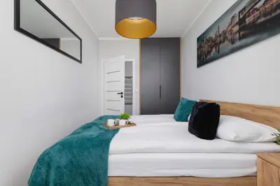 a bedroom with a white bed with a green blanket at Przestronny Apartament z Balkonem by Noclegi Renters in Kraków