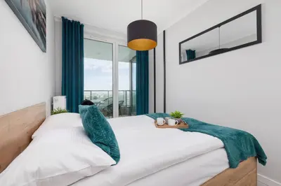 a bedroom with a bed with a green blanket on it at Przestronny Apartament z Balkonem by Noclegi Renters in Kraków