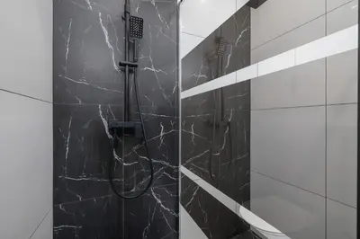 a shower in a bathroom with black marble at Przestronny Apartament z Balkonem by Noclegi Renters in Kraków