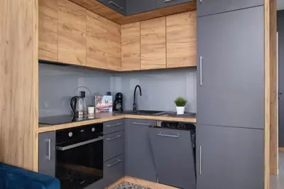 a kitchen with stainless steel appliances and wooden cabinets at Przestronny Apartament z Balkonem by Noclegi Renters in Kraków