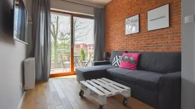 a living room with a couch and a brick wall at Rakowicka Apartment - free parking in Kraków
