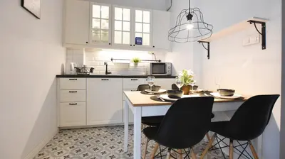 a kitchen with a wooden table with plates and wine glasses at Rakowicka Apartment - free parking in Kraków