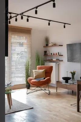 a living room with an orange chair and a table at Cityscape Fragola Apartments in Kraków