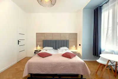a white bedroom with a large bed and a table at Roomy apartments Łobzowska Street in Kraków