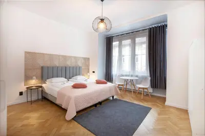 a white bedroom with a bed and a chandelier at Roomy apartments Łobzowska Street in Kraków