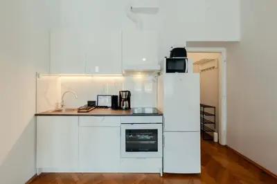 a kitchen with white appliances and a table with chairs at Roomy apartments Łobzowska Street in Kraków