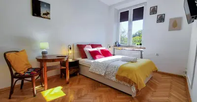 a bedroom with a bed and a desk and a window at Old Town Parkview Apartment in Kraków