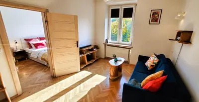 a living room with a blue couch and a bedroom at Old Town Parkview Apartment in Kraków