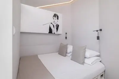 a white bedroom with a bed with a picture on the wall at Marylin Studio - Czysta 5 Street in Kraków