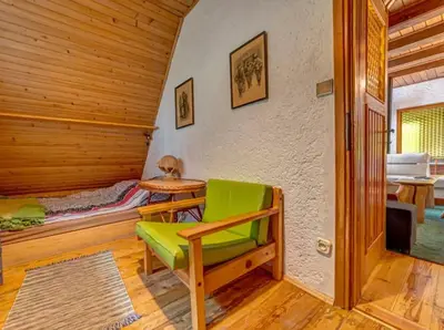 a room with a green chair and a bedroom at Klimatyczny domek w górach in Sordelówka