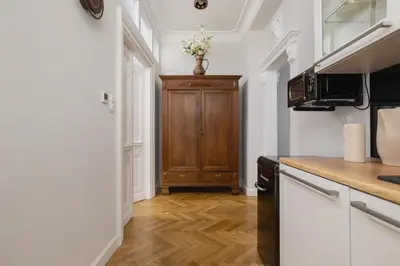 a kitchen with white walls and a wooden cabinet at 2 bedroom apartment - Sereno Fenn'a 5 street in Kraków