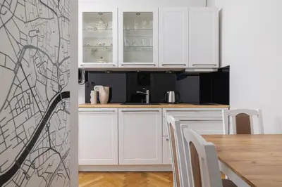 a white kitchen with white cabinets and a table at 2 bedroom apartment - Sereno Fenn'a 5 street in Kraków