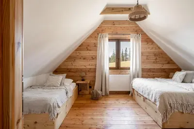 two beds in a attic bedroom with wooden walls at Mokosz in PyzÃ³wka