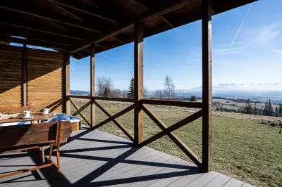 a wooden porch with a table and a view at Mokosz in PyzÃ³wka
