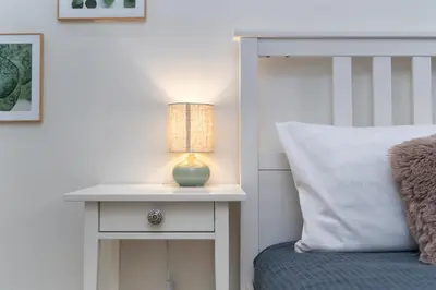 a bedside table with a lamp on it next to a bed at Nad Sudołem Stylish Apartment by BookingHost in Kraków
