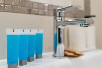 a bathroom sink with a faucet and some blue glasses at Nad Sudołem Stylish Apartment by BookingHost in Kraków