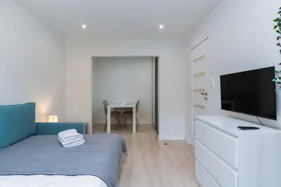 a bedroom with a bed and a flat screen tv at Nad Sudołem Stylish Apartment by BookingHost in Kraków