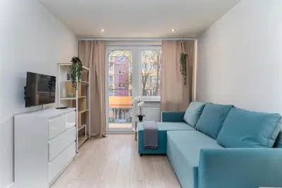 a living room with a blue couch and a tv at Nad Sudołem Stylish Apartment by BookingHost in Kraków