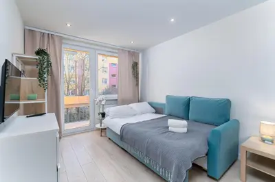 a bedroom with a blue couch and a window at Nad Sudołem Stylish Apartment by BookingHost in Kraków