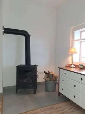 a stove in a room with a dresser and a lamp at Górska Otulina in Wilkowisko