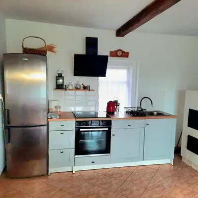 a kitchen with a stainless steel refrigerator and white cabinets at Górska Otulina in Wilkowisko