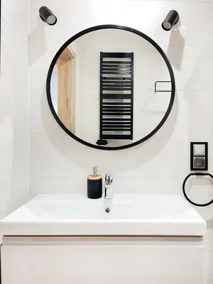 a bathroom with a white sink and a round mirror at Comfy Apartment with home cinema projector, Cracow's heart in Kraków