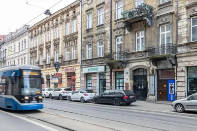 a bus driving down a city street with parked cars at Apartment with Air Conditioning in the heart of Cracow heart in Kraków