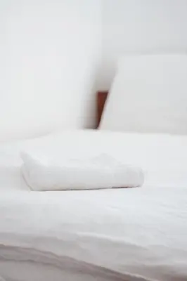 a white bed with a white pillow on it at Zajazd Hetmański-Noclegi-Nowy Wiśnicz in Nowy Wiśnicz