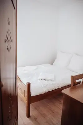 a bedroom with a bed with white sheets and a mirror at Zajazd Hetmański-Noclegi-Nowy Wiśnicz in Nowy Wiśnicz