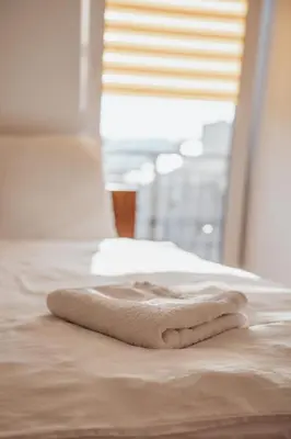 a white towel laying on a bed with a window at Zajazd Hetmański-Noclegi-Nowy Wiśnicz in Nowy Wiśnicz