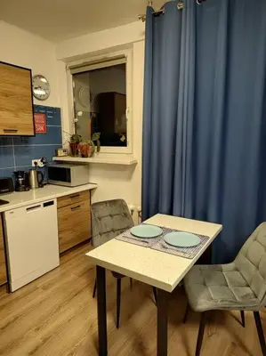 a small kitchen with a table and a blue curtain at Star Wars Climate Apartment in Kraków
