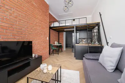 a living room with a couch and a brick wall at Studio apartment - Berka Joselewicza 5 street in Kraków