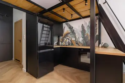 a kitchen with black cabinets and a painting on the wall at Studio apartment - Berka Joselewicza 5 street in Kraków