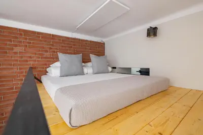 a bed in a room with a brick wall at Studio apartment - Berka Joselewicza 5 street in Kraków