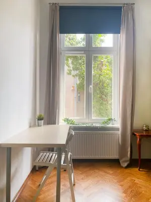 a table and chair in front of a window at Large 89m2 Apartment, 3 bedrooms and 2 bathrooms in Kraków