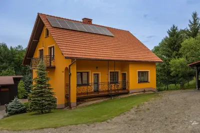 a yellow house with solar panels on the roof at Ostoja w Górach in Bieńkówka