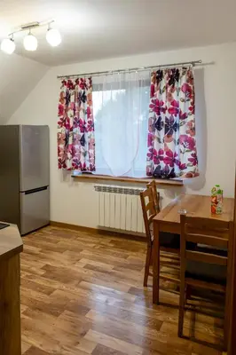 a kitchen with a table and a window with curtains at Ostoja w Górach in Bieńkówka