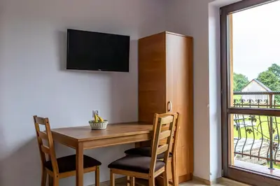 a dining room table with chairs and a television on a wall at Ostoja w Górach in Bieńkówka