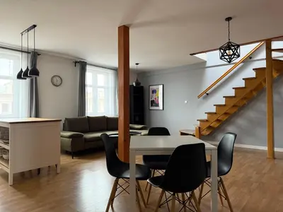 a living room with a table and chairs and a staircase at Corner Apartments in Kraków