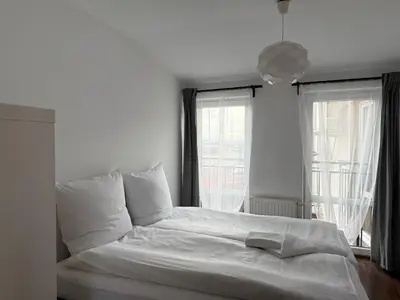 a white bed in a bedroom with two windows at Corner Apartments in Kraków