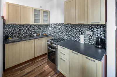 a kitchen with wooden cabinets and a stove top oven at Corner Apartments in Kraków