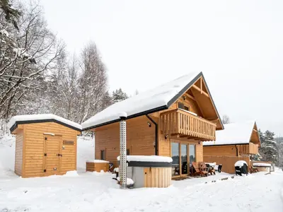 a log cabin with snow on the roof at Łysogórska Polana Domki in Mordarka