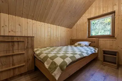 a bedroom with a bed in a wooden cabin at Łysogórska Polana Domki in Mordarka