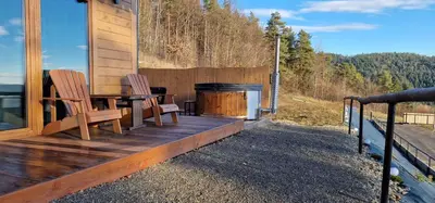 a wooden deck with two chairs and a grill at Łysogórska Polana Domki in Mordarka