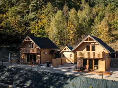 a group of log homes in front of a mountain at Łysogórska Polana Domki in Mordarka