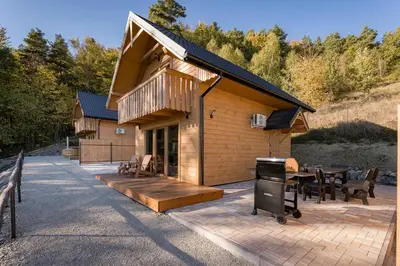 a house with a patio and a grill in front of it at Łysogórska Polana Domki in Mordarka