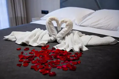 two towels and red rose petals on a bed at Zacisze pod Chełmem in Stryszów
